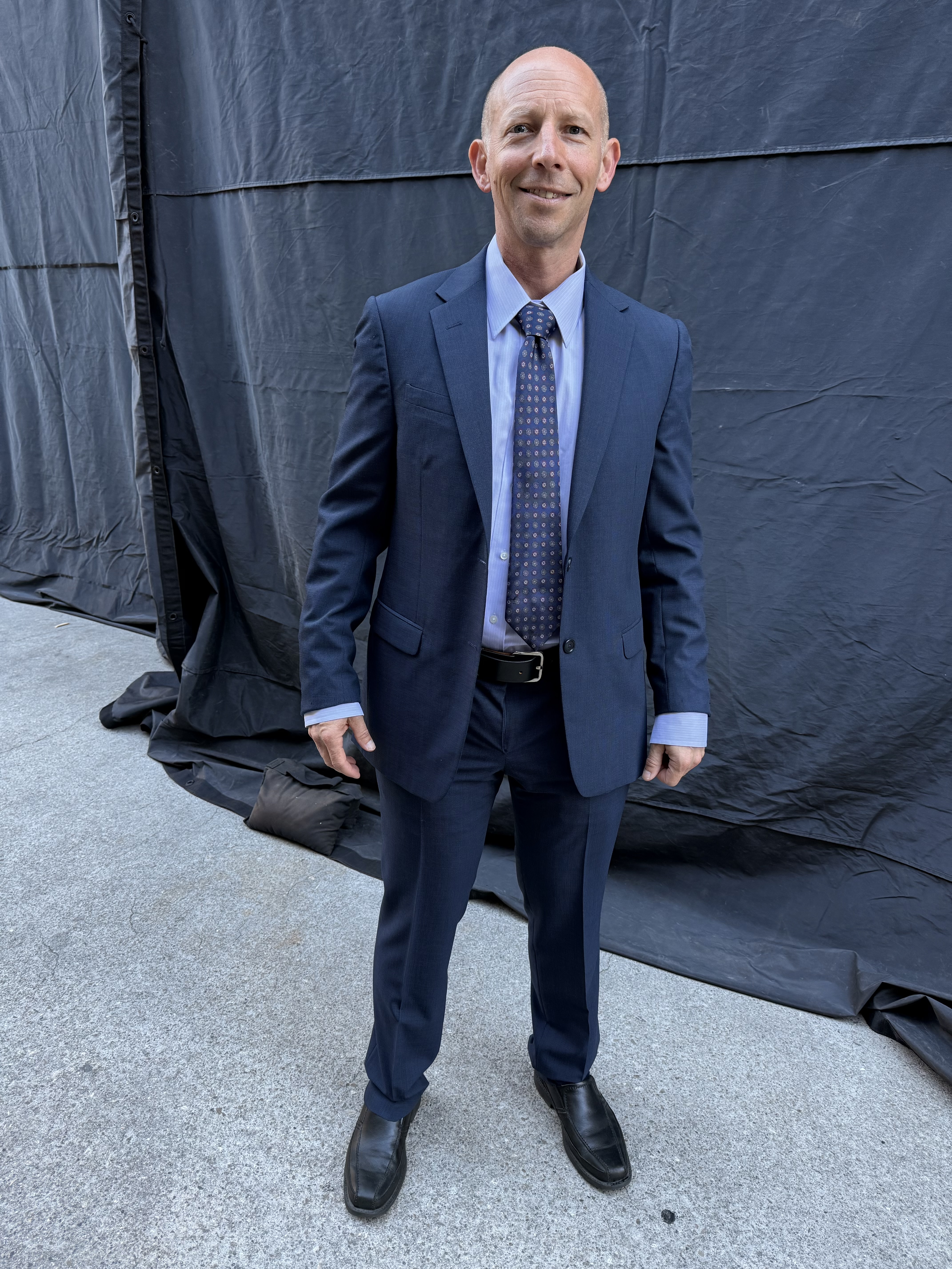Randy Loveridge in a navy suit on the set of Grey's Anatomy