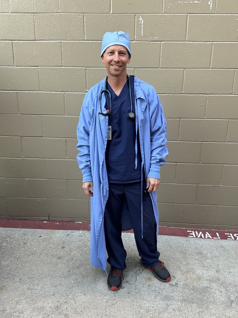Randy Loveridge in surgical scrubs, cap, and gown on the set of Grey's Anatomy
